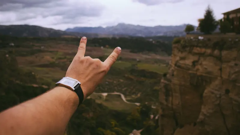 A hand making a rock sign over a valley
